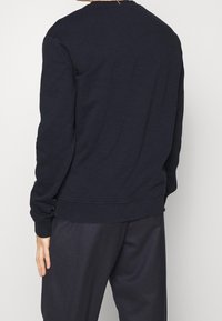 Sudadera azul marino con cuello redondo, puños y dobladillo acanalados, confeccionada en una suave mezcla de algodón, con un diseño sencillo y un ajuste relajado.