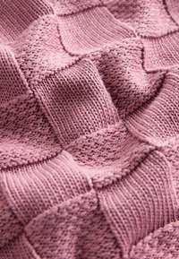 Tissu tricoté rose doux avec un motif damier texturé alternant des carrés lisses et côtelés.