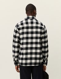 Fekete-fehér kock�ás flanel ing gallérral, gombos mandzsettákkal és lekerekített hemjével. Strukturált, puha megjelenésű anyag.