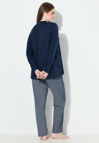 Top de manga larga azul marino con un corte relajado y aberturas laterales, combinado con pantalones azules estampados que presentan un diseño de cuadrícula de diamantes.