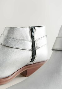 Hopeiset nahka ankle boots, joissa on sivuvetoketju, pyöreä kärki ja teksturoitu pinta; sisältää matalan ruskean puuheelin.