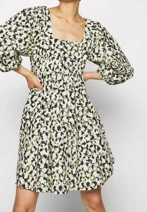Robe à imprimé floral, à manches courtes, avec un décolleté carré et des poches. Présente un corsage ajusté et une jupe évasée dans des couleurs vert, noir et crème.