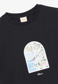 Fekete pamut póló, melyen egy színes, íves grafika látható a tengeri tájról, fákkal, épületekkel és vízzel, a mellrészen középen elhelyezve.