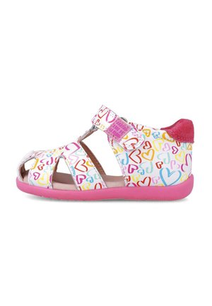 Sandalias infantiles con material sintético blanco y patrones de corazones coloridos, diseño abierto, suela de goma rosa y una correa de Velcro.