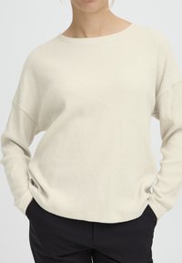 Maglione a costine in beige chiaro, con scollo rotondo e spalle scese, dal fit rilassato e maniche lunghe.