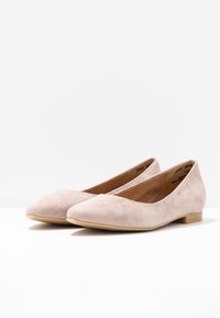 Bailarinas de ante beige con punta afilada, tacón plano y textura suave. Diseño sencillo sin herrajes visibles ni patrones.