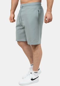 Lichte teal korte broek met een elastische tailleband en koord, voorzien van zijzakken en geborduurde logo-detail bij de zoom.