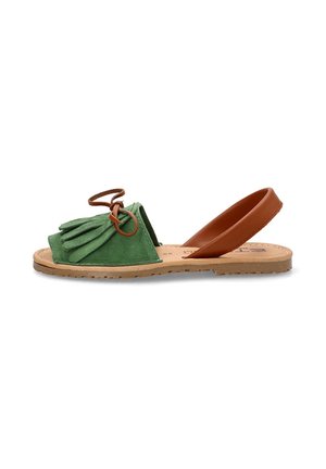Sandalia de ante verde con detalles de flecos, correa de cuero marrón, parte trasera abierta y suela de goma plana. Diseño simple para uso casual.