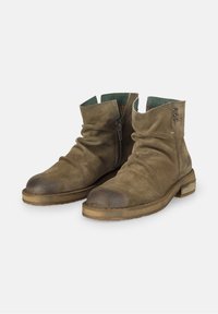 Bottes chevilles en daim marron avec un haut légèrement ébouriffé, une fermeture éclair sur le côté, un bout arrondi lisse et des accents de semelle en bois contrastés.
