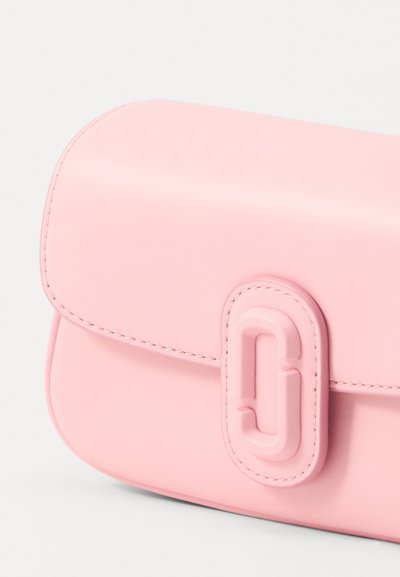 Roze kožna torba za ruke zaobljenog oblika, koja ima istaknuti kopču s logotipom, urednu šavovu obradu i glatku teksturu.