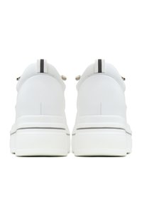 Paire de baskets à plateforme blanches vues de dos, avec une languette à tirage noire et blanche sur le talon et des semelles épaisses.