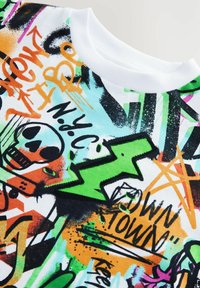 Barevné tričko s potiskem graffiti vyrobené z bavlny, bílé kulaté výstřihy, zdobené motivy lebek, blesků a městského stylu.
