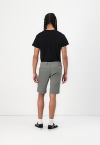 Gray shorts with a smooth texture, pockets on the back, worn with a black t-shirt and black sneakers, set against a plain white background.