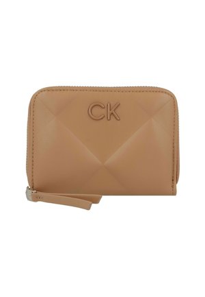 Portefeuille en cuir tan avec un motif matelassé, logo "CK" embossé, fermeture éclair et une sangle pour le poignet. Forme rectangulaire compacte. Texture lisse.