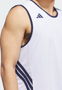 Camiseta atlética blanca con acentos en azul marino y tres franjas a lo largo del costado. El material es ligero y transpirable, diseñado para el deporte.