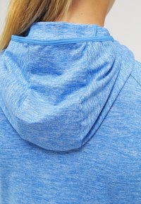 Felpa blu chiaro realizzata in tessuto testurizzato. Presenta un cappuccio morbido e arrotondato con bordo blu a contrasto e senza motivi o parti metalliche visibili.