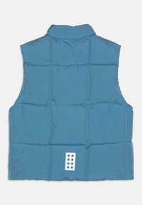 Ανοιχτό μπλε γιλέκο με κολάρο, που διαθέτει σχέδιο με κουβάρια, κυκλικά ραφή και μια λευκή ετικέτα με έξι μαύρες κουκίδες στο πίσω μέρος.