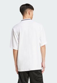 Witte polo t-shirt met korte mouwen en een kraag met zwarte strepen, in een relaxte pasvorm en van soepel katoen.