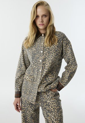 Conjunto de camisa y pantalones de estampado de leopardo, hecho de tela suave. Presenta un cuello abotonado, bolsillos de parche y acentos a cuadros en los puños.