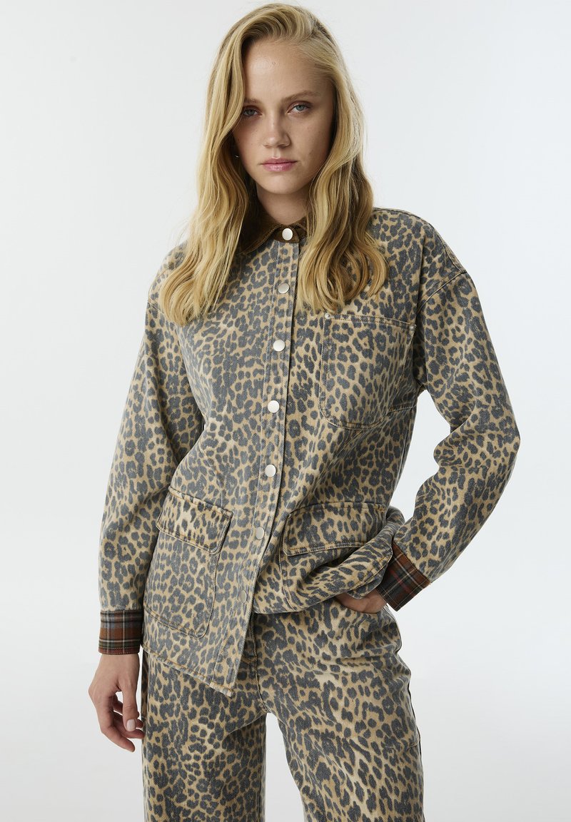 Leopardprint shirt en broek set gemaakt van zachte stof. Heeft een geknoopte kraag, opgestikte zakken en geruite accenten op de mouwen.