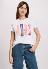 Biała koszulka z kolorowym nadrukiem w pionowe paski w odcieniach różu, granatu i kwiatowych wzorach, z złotymi akcentami oraz luźnym krojem.