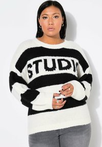 Maglione a righe bianche e nere, con vestibilità ampia, maniche larghe e la parola "STUD" in grassetto sul davanti. Morbido, in tessuto lavorato a maglia.