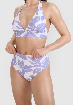 Kobieta w białym i lawendowym bikini w liściasty wzór, z topem na wiązanie na szyję i majtkami z wysokim stanem na jednolitym tle.