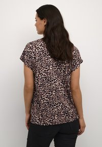 Top s krátkým rukávem s leopardím vzorem v růžové a černé barvě, lehký materiál, volný střih, zakřivený lem a jemný lesk na povrchu.