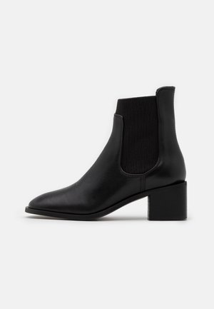 Black ankle boots with a smooth leather exterior, ribbed elastic side panels, pointed toe, and a square block heel.