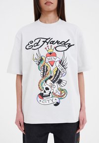 Witte katoenen T-shirt met een grote kleurrijke grafische print van een schedel, een arend, slangen en de tekst "Ed Hardy New York City."