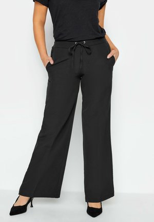 Zwarte wijde broek van zacht materiaal, met een elastische tailleband en trekkoord en zijzakken. Gladde textuur, casual ontwerp.
