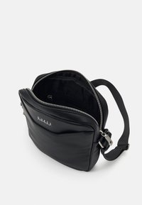 Borsa a tracolla in pelle nera con chiusura a zip, dotata di una tasca frontale e minuteria in metallo argentato. Texture liscia e logo del marchio visibile.