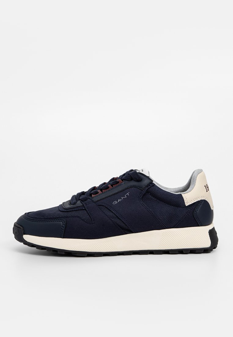 Marineblaue Sneaker mit Obermaterial aus Textil und Synthetik, cremefarbener Sohle, Schnürverschluss und Logodetails. Verfügt über eine gepolsterte Ferse und eine strukturierte Oberfläche.