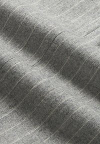 Tessuto grigio con un aspetto testurizzato, caratterizzato da sottili strisce bianche disposte parallelamente. Materiale morbido e intrecciato con fibre visibili.