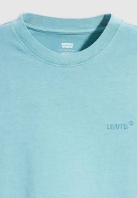 Tricou Levi's de culoare albastră deschisă, fabricat din bumbac, cu guler rotund, mâneci scurte și un logo brodat pe partea stângă a pieptului.