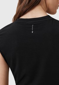 T-shirt nera con maniche corte, caratterizzata da un piccolo dettaglio del logo bianco sul collo sul retro. Tessuto dalla texture liscia.