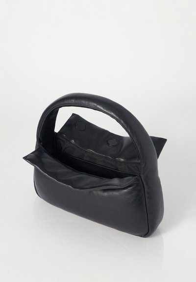 Μαύρη τσάντα από τεχνητό δέρμα με στρογγυλή λαβή, μαλακή υφή και κλείσιμο με κουμπί. Ο εσωτερικός χώρος διαθέτει μία μόνο θήκη.