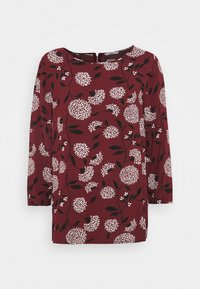 Blusa bordeaux con motivo floreale bianco e nero, maniche a tre quarti, scollatura rotonda e vestibilità rilassata.