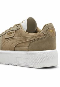 Sneaker in suede marrone chiaro con suola in gomma bianca, caratterizzato da una punta rotonda, design con lacci e dettagli in oro sul lato e sulla lingua.