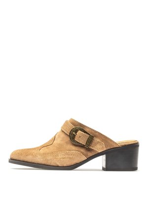 Mule de ante color tostado con punta puntiaguda, costuras decorativas, correa ancha, hebilla de latón ornamentada y tacón bloque negro de altura media.