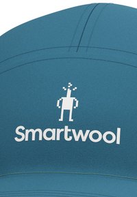 Teal cap featuring "Smartwool" logo in white with a pixelated character design; smooth fabric, rounded crown, and contrast stitching detail.