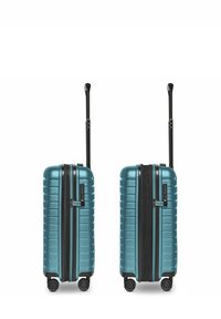 Due valigie rigide di colore teal con maniglie nere estese e quattro ruote, mostrate chiuse con la zip e parzialmente aperte per l'espansione.