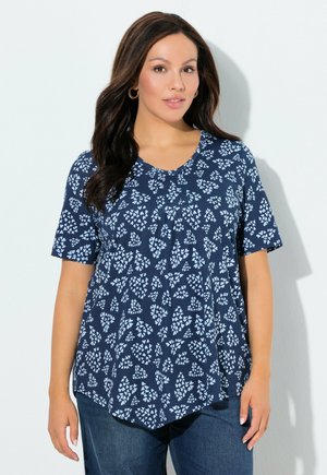 Granatowy krótki rękaw top z białym kwiatowym wzorem; dekolt w serek; lekka tkanina; luźny krój; zaokrąglony dół, zestawiony z dżinsowymi spodniami.