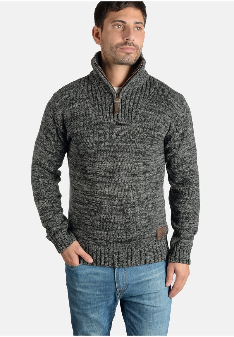 Suéter de punto gris y negro con cremallera de cuarto, con un patrón texturizado, puños y dobladillo acanalados, que presenta un parche de logo de cuero marrón.