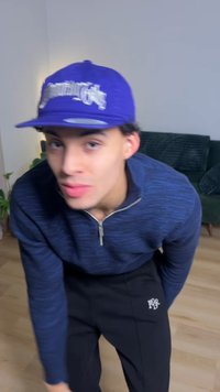 Pull à fermeture éclair bleu avec motif texturé, pantalon noir avec logo, et casquette bleue avec inscriptions blanches, sur un fond clair.