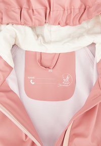 Rosa wasserdichte Jacke mit Rüschensaum, weißem Innenfutter und einem Bereich für Name und Kontaktdaten.