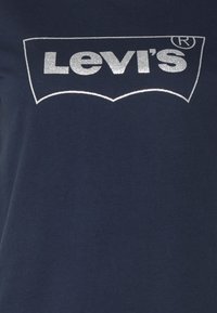 Námořnická modrá tričko z bavlny s třpytivým stříbrným logem "Levi's" na hrudi, s kulatým výstřihem a krátkými rukávy.