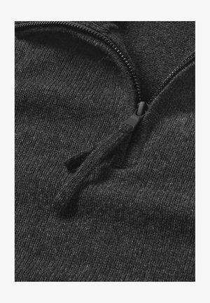 Black zip-up sweater made from soft, textured fabric with a partial zipper at the neckline and visible stitching details.