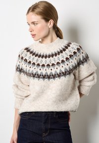 Gruby sweter dzianinowy w kolorze kremowym z wzorzystym karczkiem w brązowych i szarych odcieniach. Posiada prążkowany dekolt i mankiety, szerokie rękawy oraz miękką teksturę.