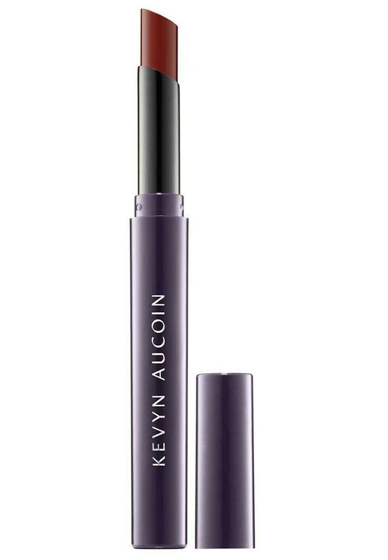 Lippenstift in einem schlanken, metallischen lila Gehäuse. Das Produkt verfügt über eine geschwungene, reichhaltige braun-rote Mine und einen kontrastierenden schwarzen Drehmechanismus.